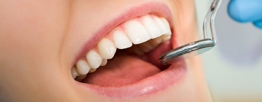 Close-up of patients open mouth before oral inspection with mirror near by